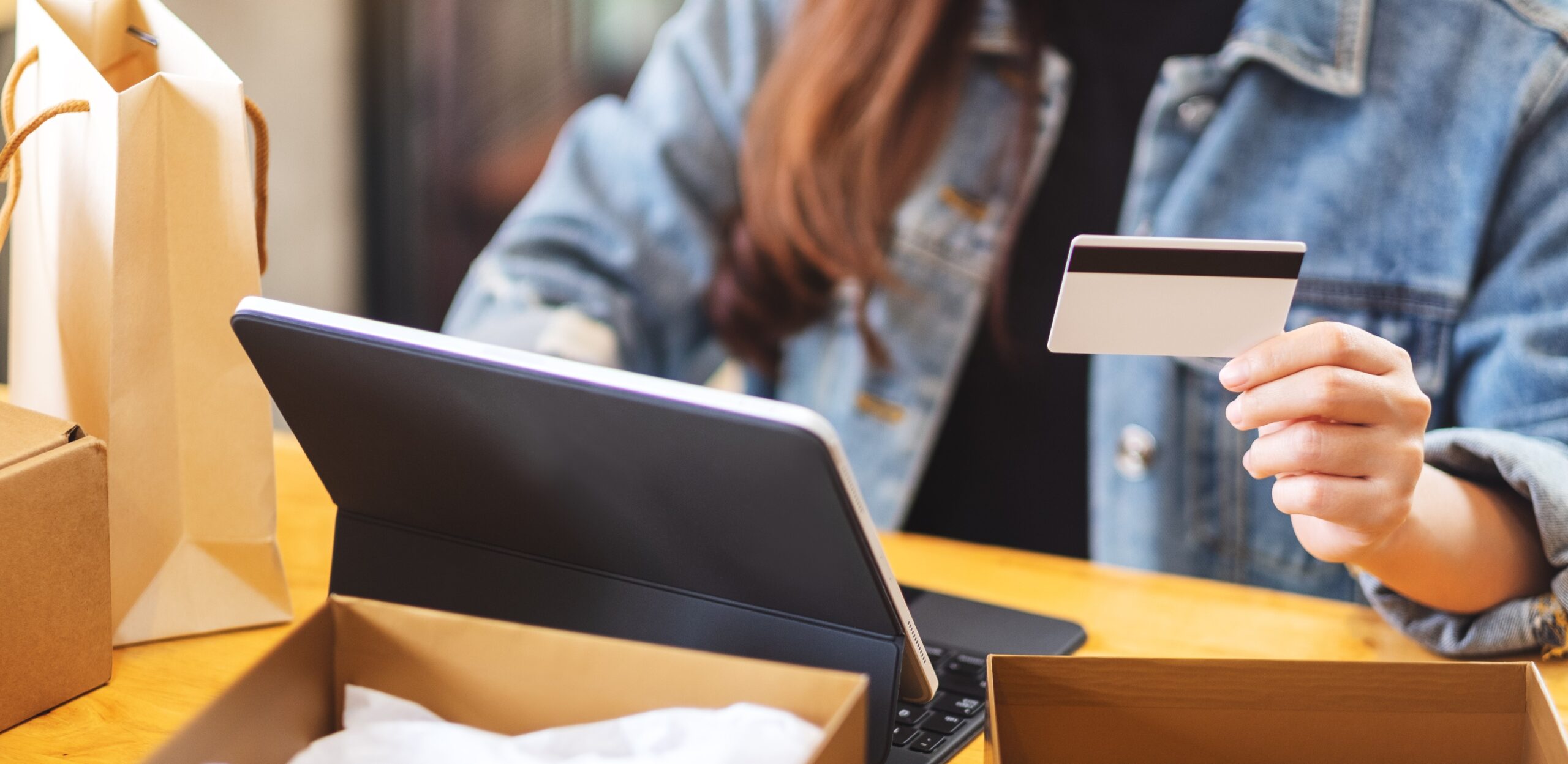 Webshopmedewerker pakt een bestelling in en houdt een betaalpas vast