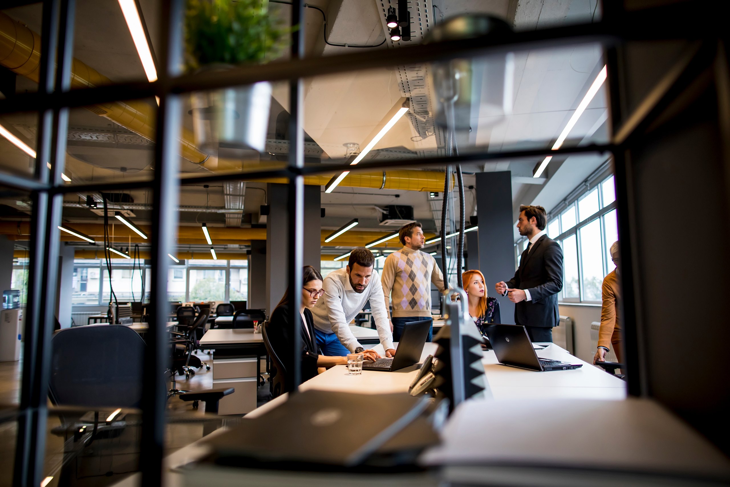 Team in overleg rond een bureau met laptops op kantoor