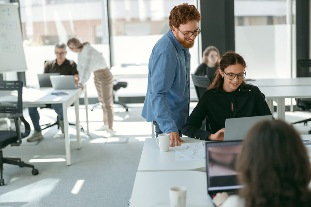 Twee collega's bekijken samen een klantenportal op een laptop