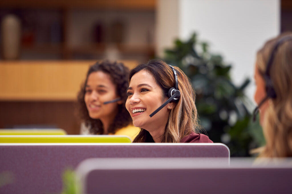 Lachende klantenservicemedewerker met headset in gesprek met een klant